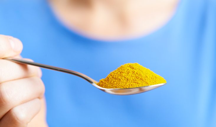 Close Up Of Woman With Spoonful Of Tumeric Powder